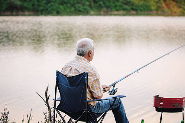 istock Two elder men fishing together on a calm lake 2227029270