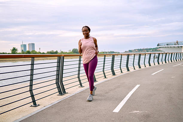 istock Young woman jogging on a riverside promenade 2227030543