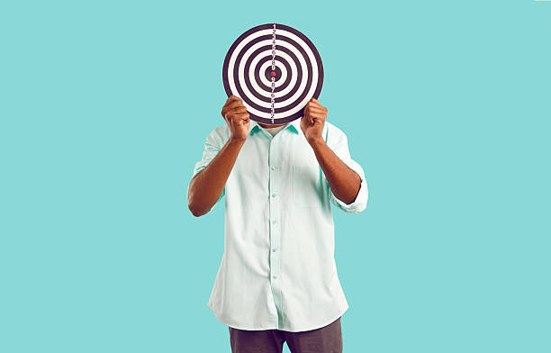 istock Anonymous man hides face behind dart board, symbolizing selection of target audience or targeted ads 2227031775