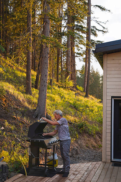 istock Mature man uses bbq on cottage deck 2227031937