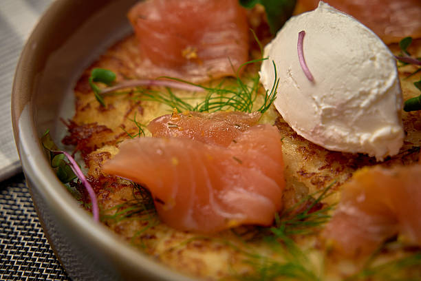 istock A scrumptious dish featuring delicate smoked salmon atop a golden crispy base, garnished with fresh herbs and creamy topping for an exquisite culinary experience. 2227033707