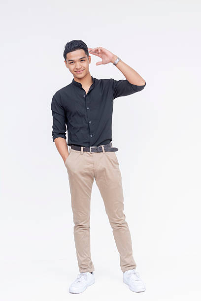 A friendly and handsome Filipino man making a loose salute gesture. Wearing black polo shirt and khaki pants. Full body photo, isolated on a white background.