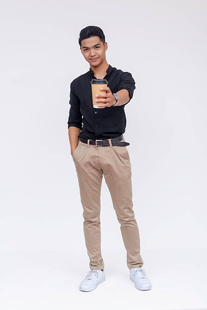 Confident young Filipino adult holding a coffee cup, dressed in smart casual attire, posing against a white backdrop.