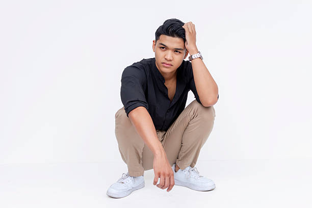 istock A young asian man crouching down and scratching his head, looking frustrated. Studio shot isolated on a white background. 2227034942