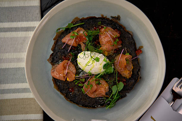 istock A Gourmet Dish Featuring Delicate Smoked Salmon, Poached Egg, and Fresh Microgreens Nestled on a Rich Black Base Garnished to Perfection 2227035151