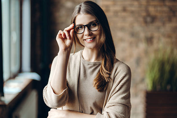 istock Smiling young woman adjusting eyeglasses in modern office 2227036182