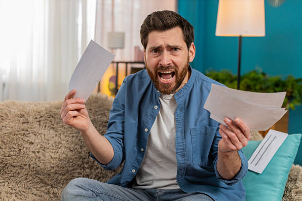 istock Man throwing home utility bills on sofa, desperate about financial debt, frustration 2227041717