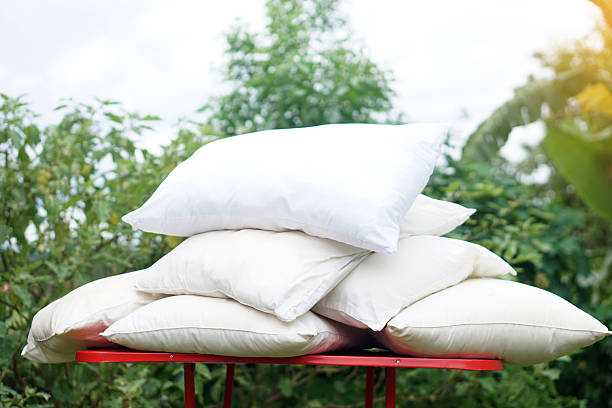istock Stack of white pillows exposed to natural sunlight on a red table outdoor. Concept, dust mite removal, refreshing fabric, and promoting bedding hygiene and health. 2227048093