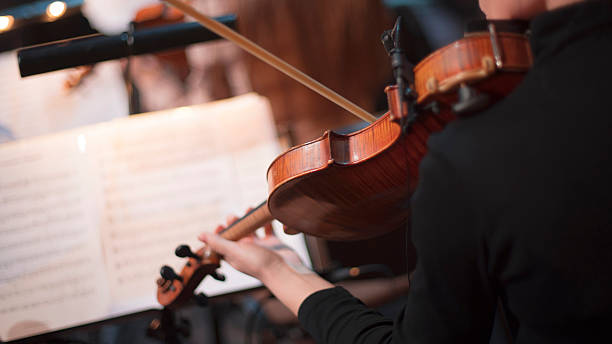 istock girl playing violin in orchestra on stage 2227052502