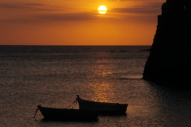 Cádiz, Spain. 29 August 2007. At sunset, the sun illuminates the silhouette of two fishing boats anchored on the shore of La Caleta beach, in the city's historic center.