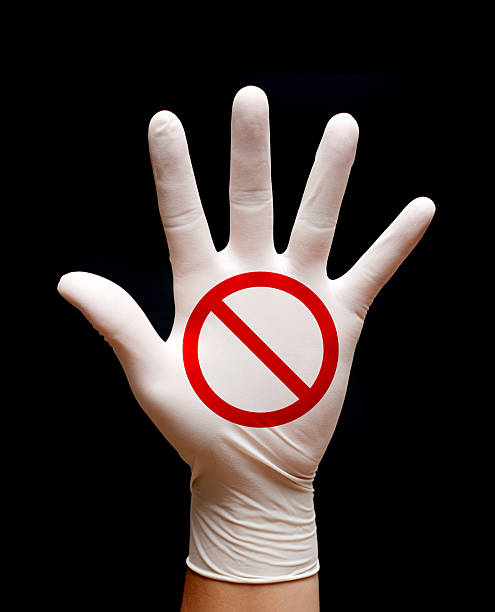 Stop! Prohibition sign on hand wearing protective gloves isolated on black.