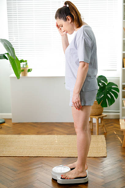 istock Woman checking weight on scale standing at home 2227070409