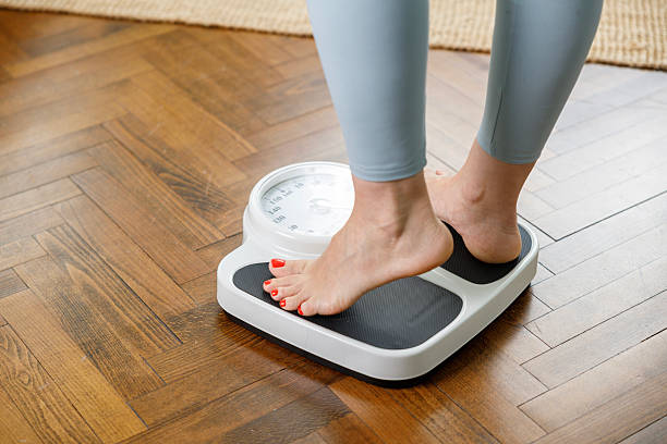 istock Woman checking weight on scale at home 2227070410