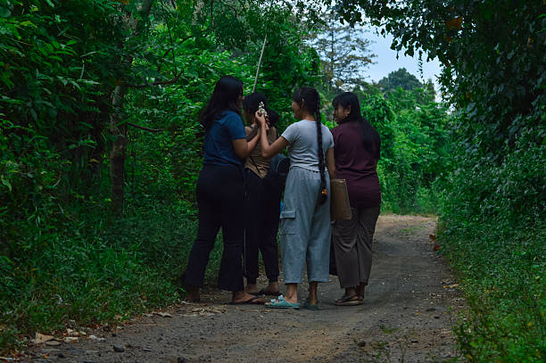 Amid the thick greenery of the forest, the girls gently pick small wildflowers from the side of the path, enjoying the fresh air and natural beauty.