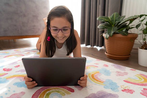 istock Little girl using a digital tablet while lying on the floor at home 2227076496
