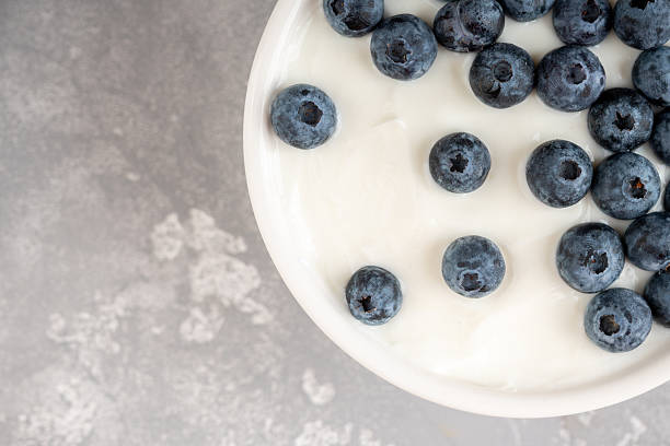 istock Fresh ripe blueberries on the white plain yogurt. Healthy desserts. 2227083550