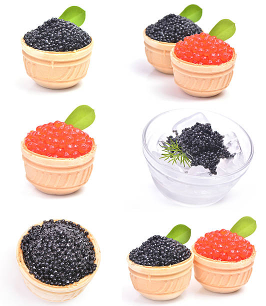 A close-up shot captures an unrecognizable server presenting a dark wooden tray filled with numerous elegant appetizers. The appetizers are small, two-toned cones filled with vibrant red salmon roe or caviar, and garnished with fresh green herbs.