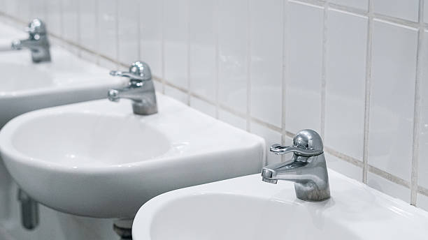 istock Public bathroom with white ceramic sinks and chrome faucets on clean wall 2227084255