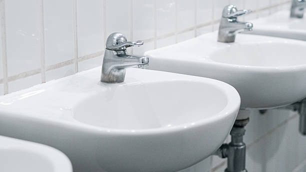 Public bathroom with white ceramic sinks and chrome faucets on clean wall