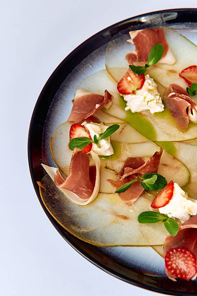istock Deliciously Crafted Plate Featuring Thinly Sliced Pears, Creamy Cheese, Savory Prosciutto, and Fresh Strawberries Artfully Arranged for an Exquisite Culinary Experience 2227086096