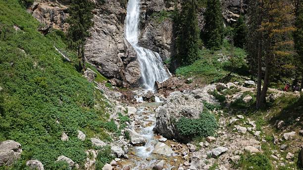 istock Waterfall cascading down rocky mountainside surrounded by lush greenery 2227087446