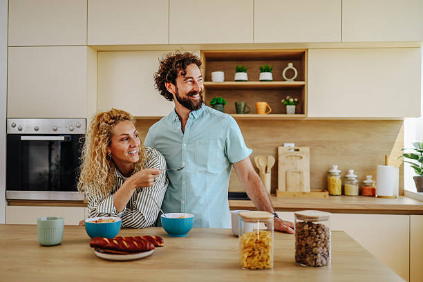 istock Young couple eating breakfast in modern kitchen, looking away and smiling 2227087676