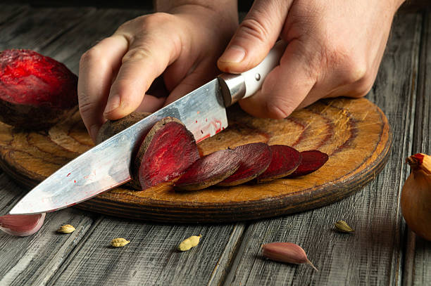 istock A person is carefully slicing vibrant beetroot into thin rounds on a rustic wooden board. The kitchen is warmly lit, creating a cozy atmosphere perfect for cooking 2227091330