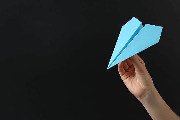 istock Woman with light blue paper plane on black background, closeup. Space for text 2227092364