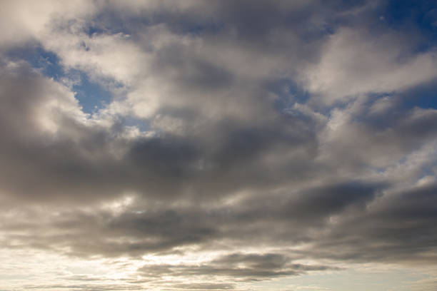 The sky is filled with clouds, but the sun is still shining through, creating a serene and peaceful atmosphere. The clouds are scattered throughout the sky, with some larger