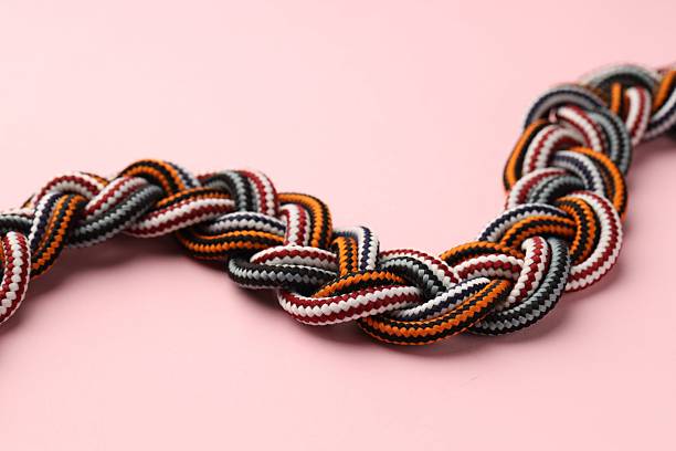 istock Braided colorful ropes on light pink background, closeup. Unity concept 2227093966