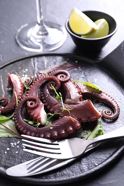 istock Tasty boiled octopus tentacles, microgreens, salt and cutlery on grey table, closeup 2227094019