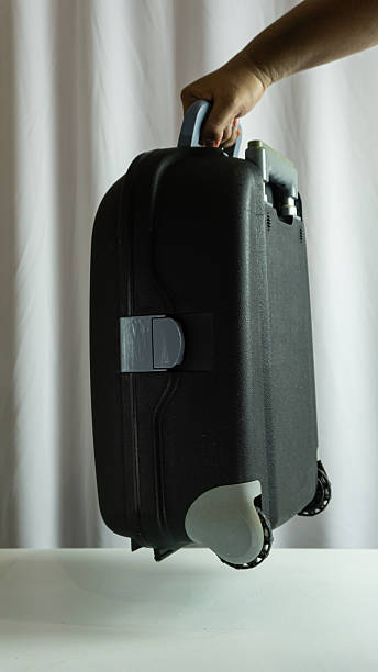 istock Portrait frame showing hand lifting suitcase, clean white textile background, modern travel concept with personal movement and lightweight luggage idea 2227094359