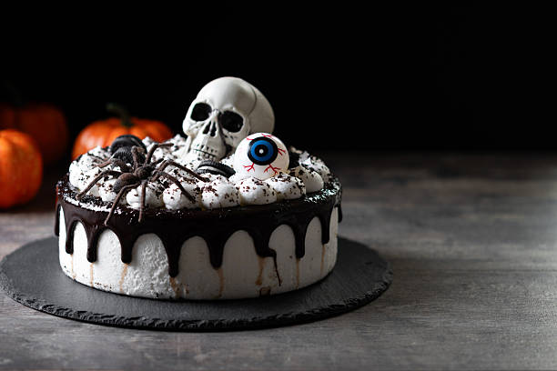 Spooky Halloween chocolate Cake with Skull, Eyeball, and Spider Decoration on dark background