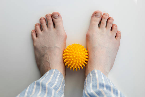 istock Female feet with flatfoot and bunions using massage ball on white background. 2227103287