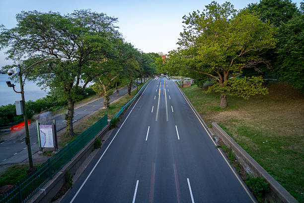istock Road lined with trees and blurred car lights. 2227106780