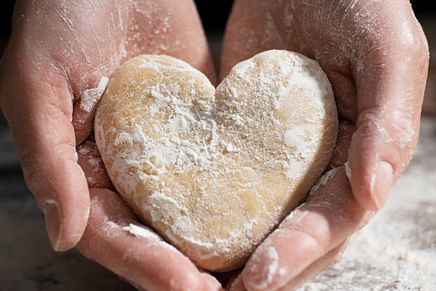 istock Baking concept. Caucasian female hands holding heart shaped dough. 2227111670