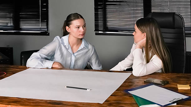 istock Two women engaged in discussion at a desk in a modern office setting 2227113870