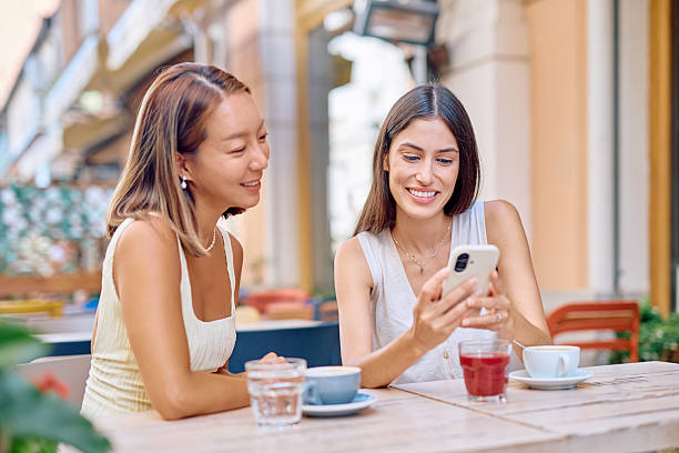 istock Two young women looking at smartphone sitting at cafe table 2227118328