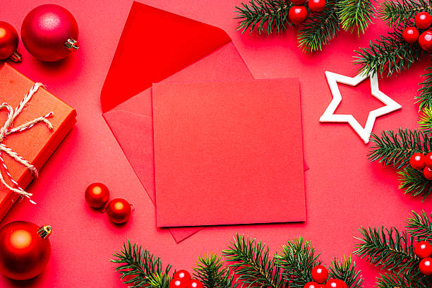 Blank greeting card or invitation and envelope for Christmas Holidays, red colored background. Flat lay and decor, gift box and fir tree border
