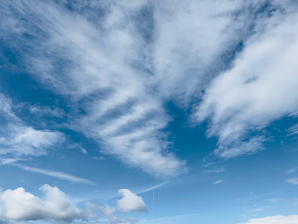 The bright blue sky is filled with a variety of fluffy white clouds, creating a serene and expansive atmosphere.