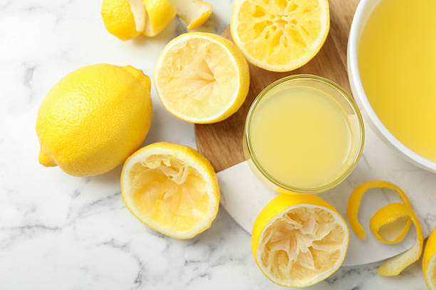 istock Fresh lemon juice and squeezed fruits on white marble table, flat lay 2227122801