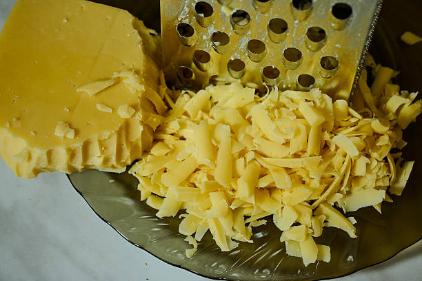 istock Grated Cheese on Red Grater in Kitchen Bowl 2227132364