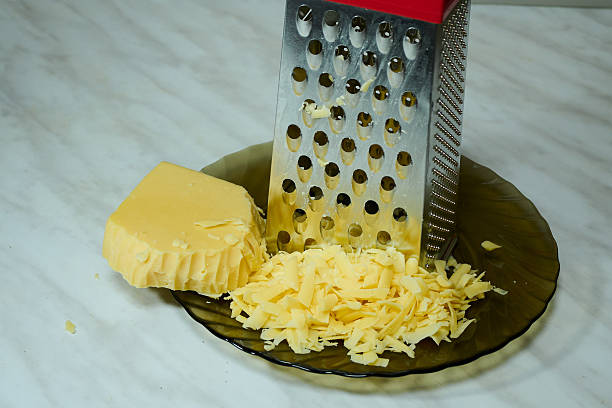 istock Grated Cheese on Red Grater in Kitchen Bowl 2227132365