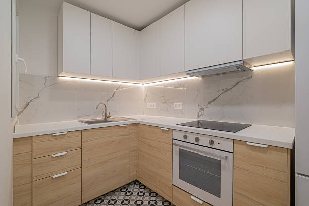 istock Modern kitchen with white cabinets and wooden accents. Features a marble backsplash, stainless steel appliances, and patterned floor tiles. 2227132544