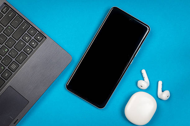 istock Laptop, Smartphone, and Wireless Earbuds on Blue Background for Work or Study.  Modern Digital Workspace and Tech Gadgets Concept 2227133932