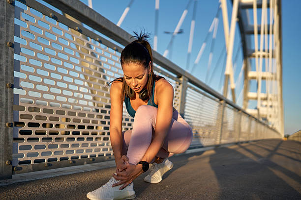 istock Young sportswoman suffering ankle pain while exercising on a bridge 2227135044