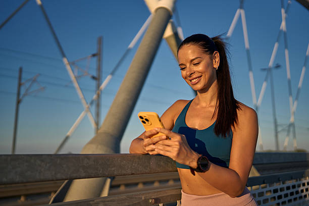 istock Young sportswoman using smartphone on a bridge at sunset 2227135060