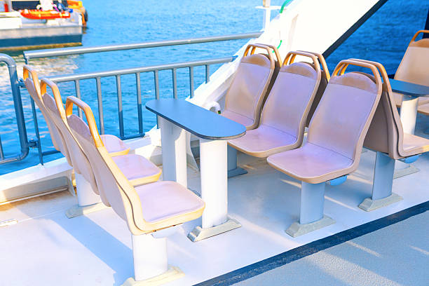 Outdoor seating on a boat deck, with a table in between. Row of seats perfect for a relaxing ferry boat ride