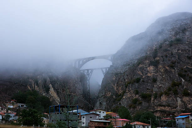 A dramatic train crosses the Veresk Railway Bridge, a striking masonry arch bridge soaring 110 m above a steep Alborz Mountain valley, with a 66 m arch span. Constructed in 1934–1935 under the Danish‑led consortium Kampsax, the engineering team included German, Austrian, and Danish engineers, later joined by Italians led by Cesare Delleani \nKnown locally as Pol‑e Piroozi (“Bridge of Victory”), it earned its name during World War II, when Allied forces relied on it to supply the Soviet Union via Iran, after Hitler demanded its destruction—a request refused by Reza Shah This iconic structure is part of the Trans‑Iranian Railway, inaugurated in December 1935, linking Tehran with the Caspian region through dense forest and rugged terrain. It symbolizes international technical collaboration and is now a UNESCO World Heritage section designated in 2021