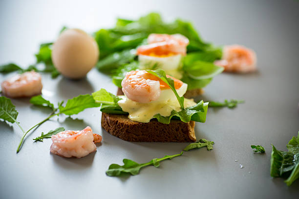 Sandwich with egg and shrimp on gray background from above.